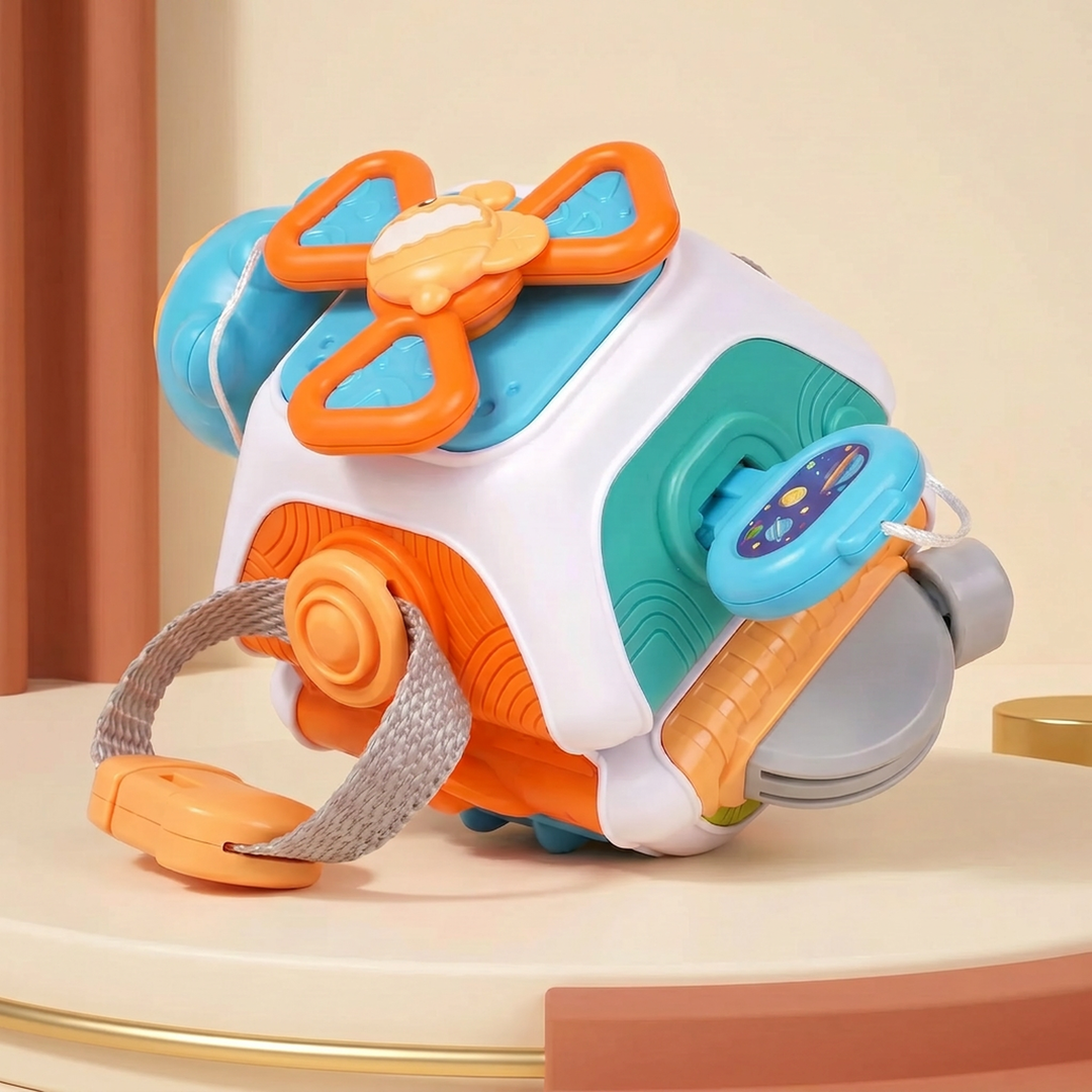 The plastic sensory busy ball showing the red steering wheel, butterfly spinner and fabric strap