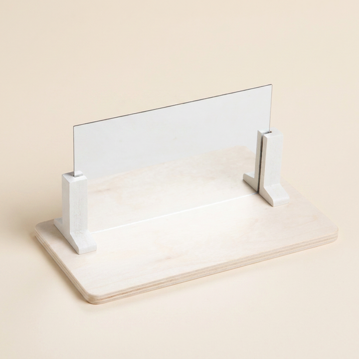 The wooden base with the acrylic mirror held upright by two white stand blocks