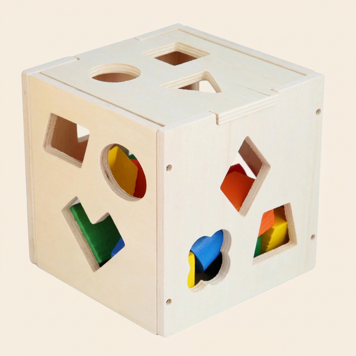 Wooden shape-sorter box on warm cream - natural pine cube with shaped holes and colorful wooden blocks