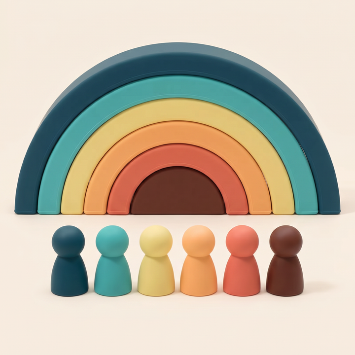 Silicone rainbow stacker on warm cream - six nested arches stacked into a rainbow with six matching peg dolls