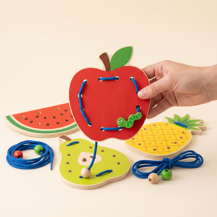Wooden apple lacing board half-threaded with the blue worm cord, the other fruit boards behind