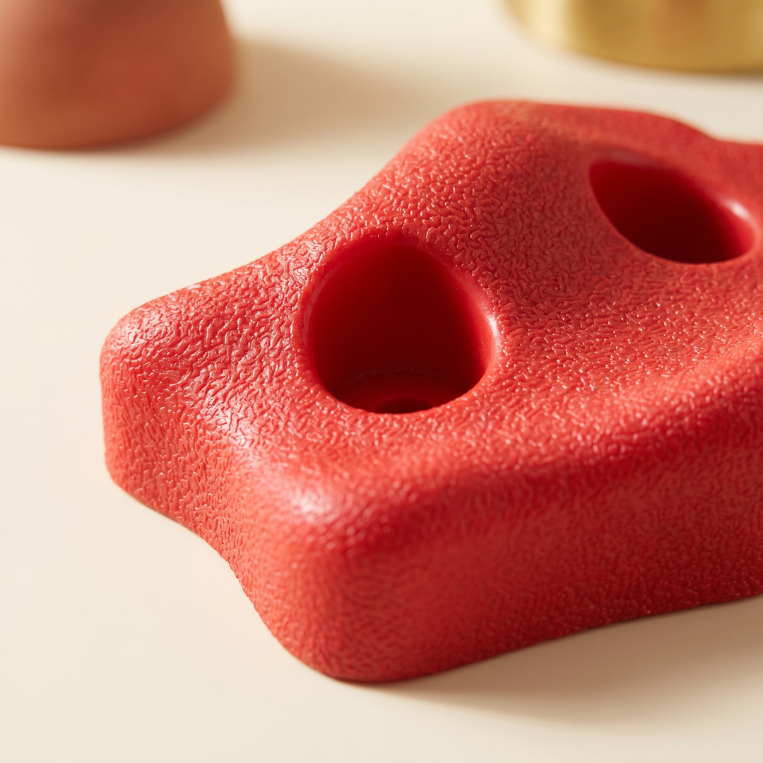 Close-up of a red climbing hold showing textured grip surface and bolt holes