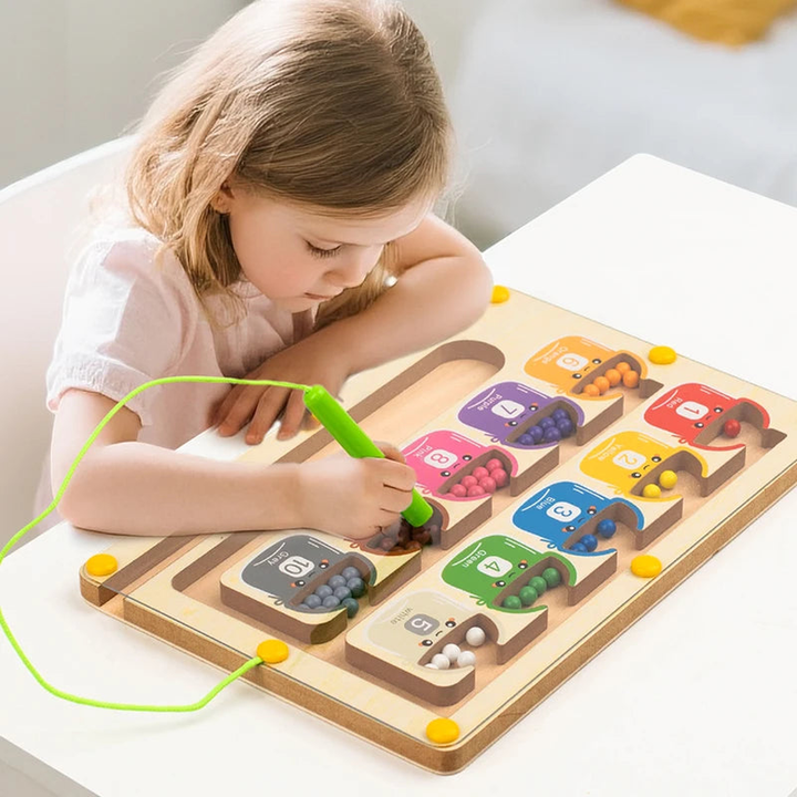 A young child playing the wooden bead maze, steering a bead with the green magnet pen