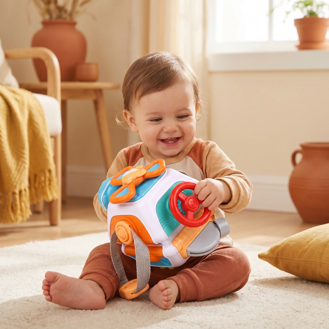 A happy toddler holding the colourful busy ball and turning the red steering wheel