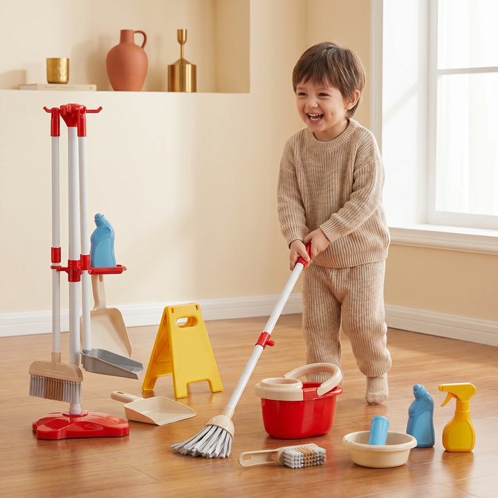 A young child pushing the child-size spinning mop across the floor with the toy bucket nearby