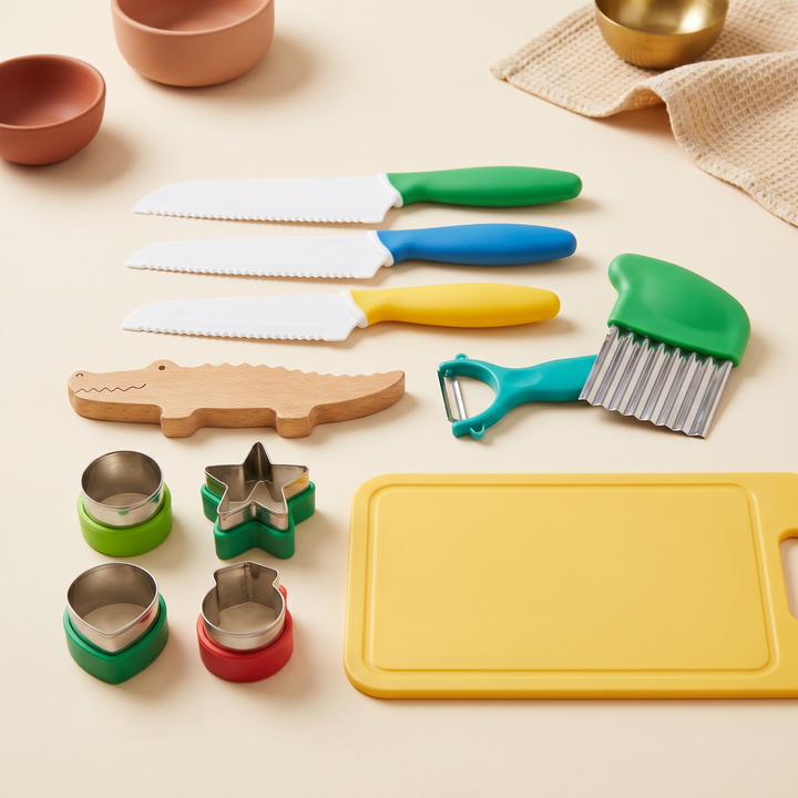 The kids cooking tools set laid out - knives, peeler, whisk, crinkle cutter, shape cutters and board